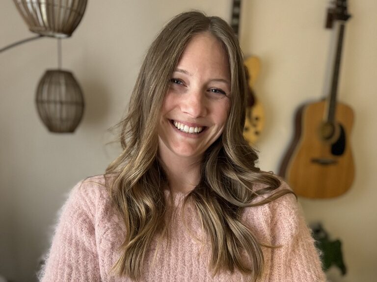 Photo of the owner of Meltdown Candleworks holding candles in her arms and smiling.