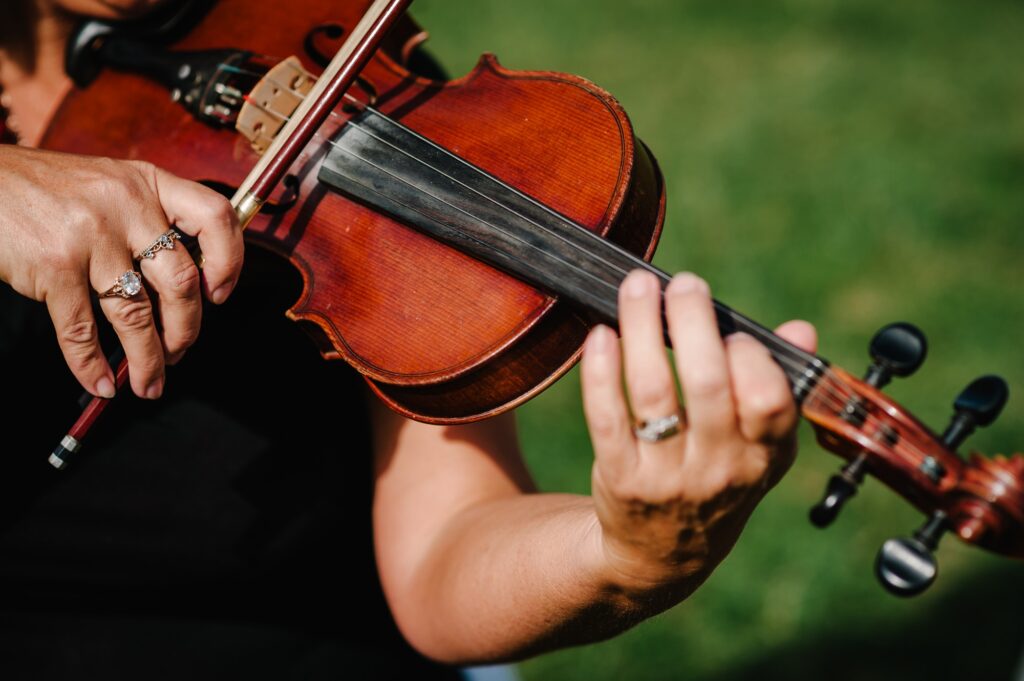 Violin player hands. Violinist playing violin on background of field. Performance on nature.
