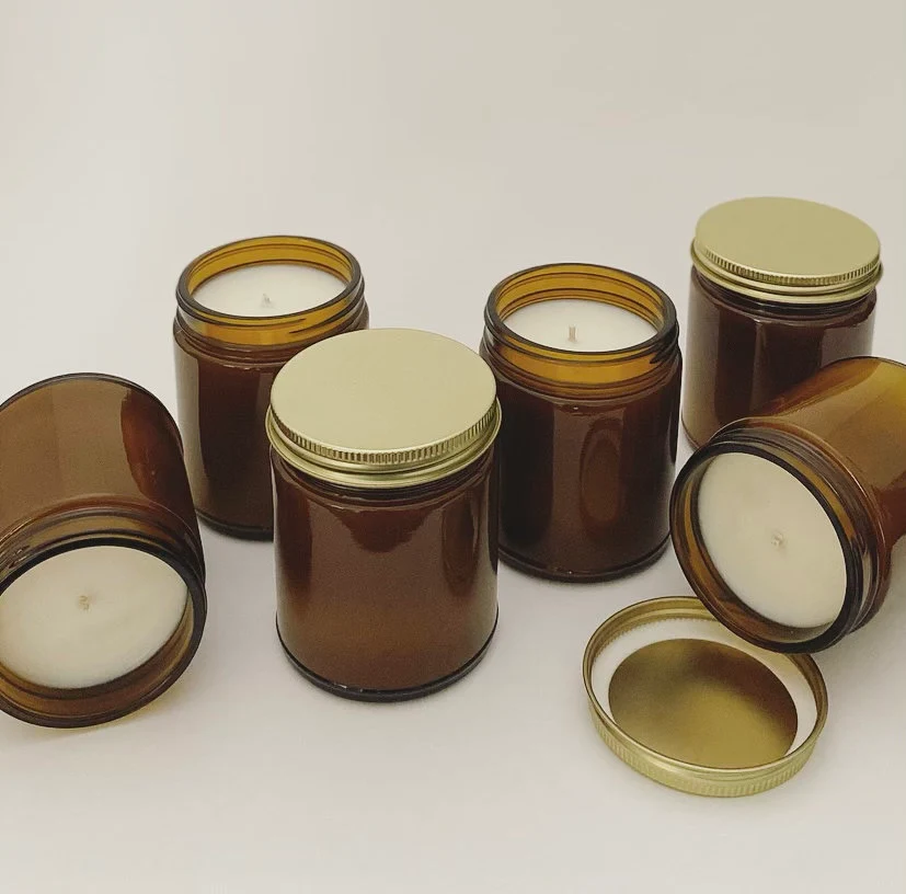 A pile of 8oz amber jar candles made of soy wax.